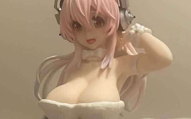 Figurka anime z różowymi włosami i słuchawkami.