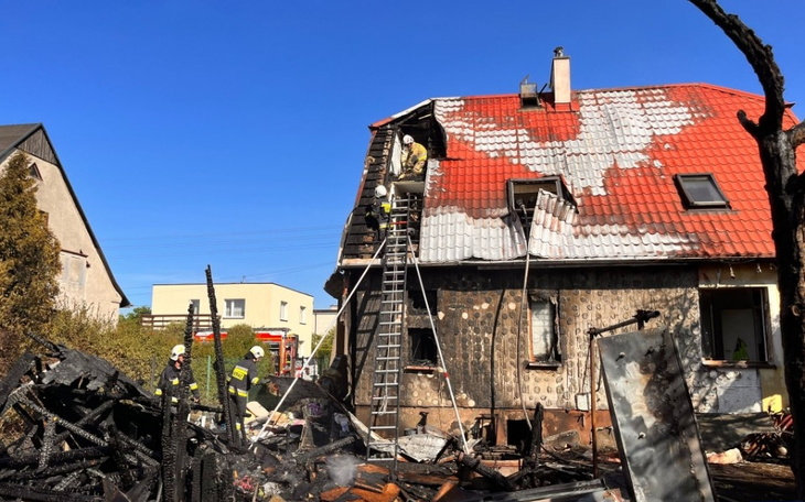 Strażacy gaszą pożar domu, zniszczone mury i dach.