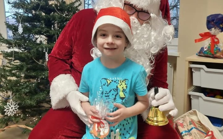 Dziecko na kolanach Świętego Mikołaja, uśmiechnięte.