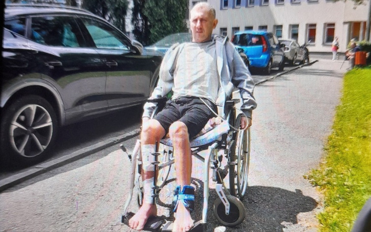 Mężczyzna na wózku inwalidzkim, siedzący na chodniku.