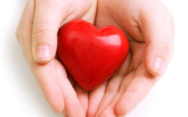 Dwie dłonie trzymają czerwone serce, symbol miłości.