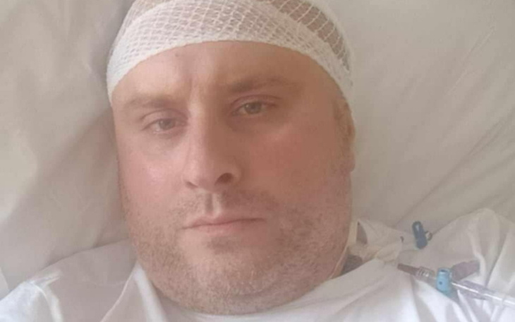 Mężczyzna w szpitalu z opatrunkiem na głowie.