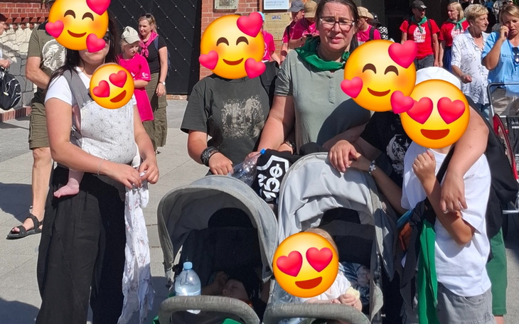 Rodzina z dziećmi i wózkami na tle festiwalu.