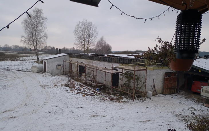 Zimowy widok na opuszczony budynek w wiejskim otoczeniu.
