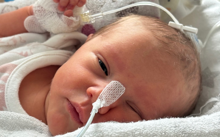 Noworodek z rurką tlenową, leży w szpitalnym łóżku.
