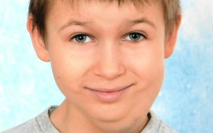 Portret uśmiechniętego chłopca na niebieskim tle.