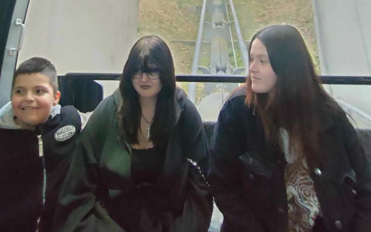 Trzy osoby w kolejce linowej, uśmiechnięte i zrelaksowane.