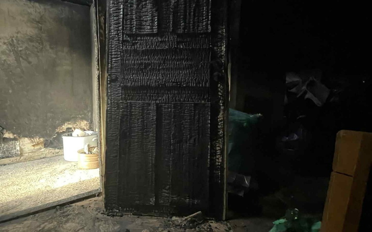 Zniszczone drzwi po pożarze, z czarnym popiołem.