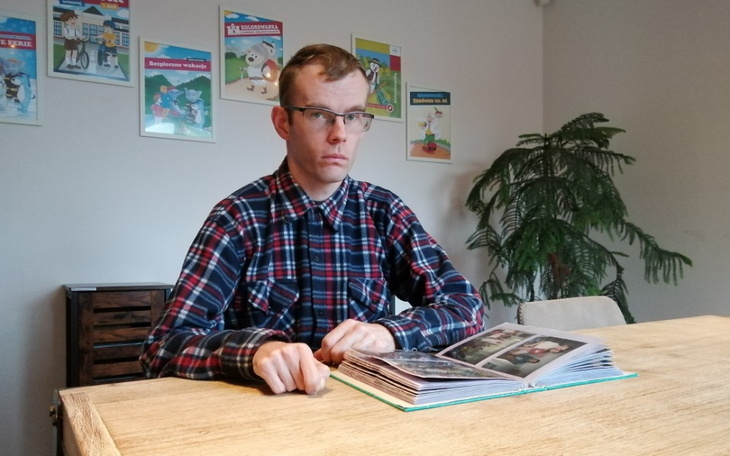 Mężczyzna w okularach przeglądający album ze zdjęciami.