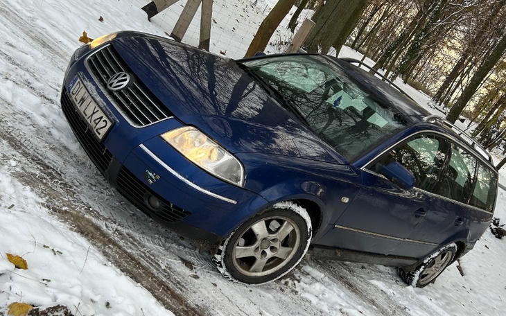 Niebieski samochód na zaśnieżonej drodze w lesie.