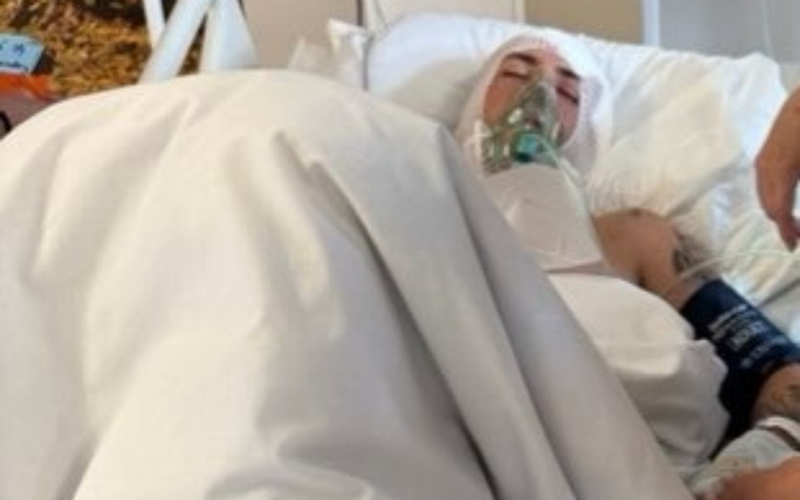 Osoba leżąca w szpitalnym łóżku, podłączona do aparatury.