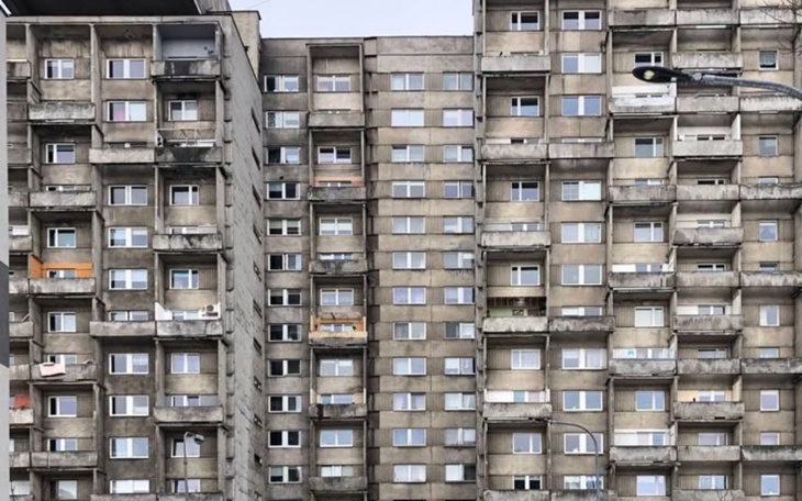 Wielopiętrowy blok mieszkalny, szare elewacje.