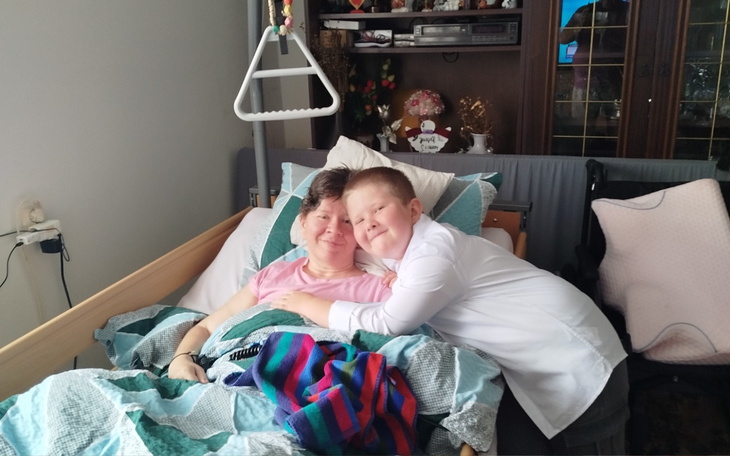 Chłopiec przytulający się do mamy w łóżku.