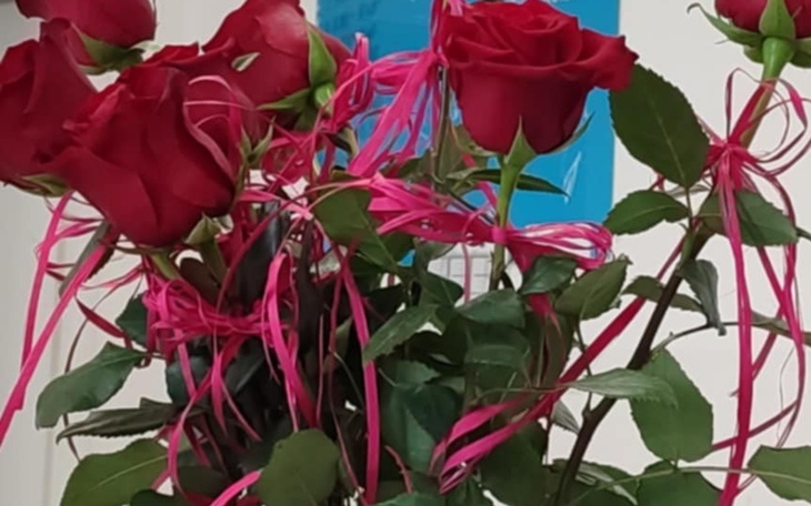 Bukiet czerwonych róż z różowymi wstążkami.