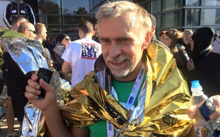 Uśmiechnięty mężczyzna po biegu, owinięty w złotą folię.