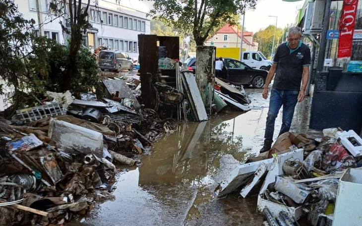 Mężczyzna przeszukujący zniszczoną okolicę po powodzi.