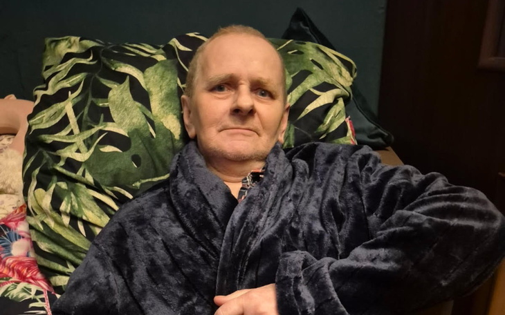 Mężczyzna w szlafroku, siedzący na kanapie w salonie.