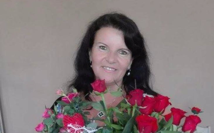 Kobieta z bukietem róż, uśmiechająca się do kamery.