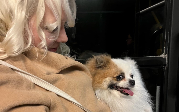 Kobieta z psem na rękach, oboje uśmiechnięci.