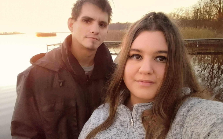 Para na tle zachodzącego słońca nad wodą.