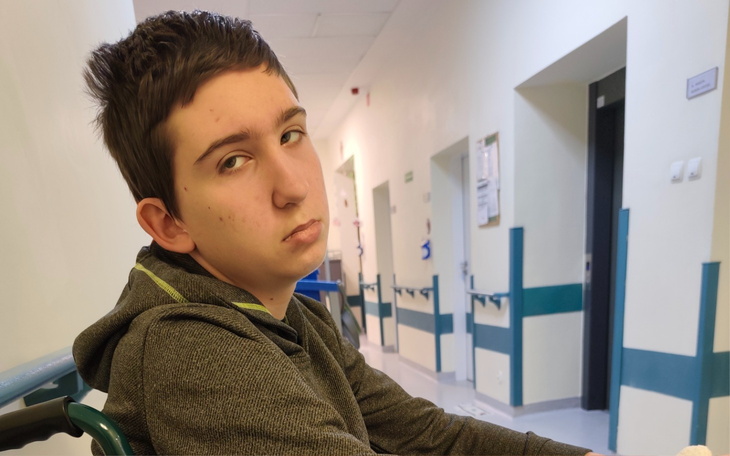 Chłopiec w szpitalu, z wyrazem smutku na twarzy.