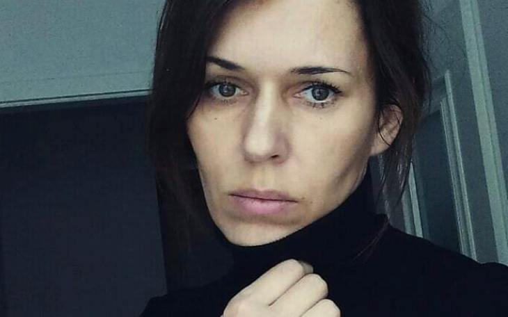 Portret kobiety w czarnym swetrze, z zamyślonym wyrazem twarzy.