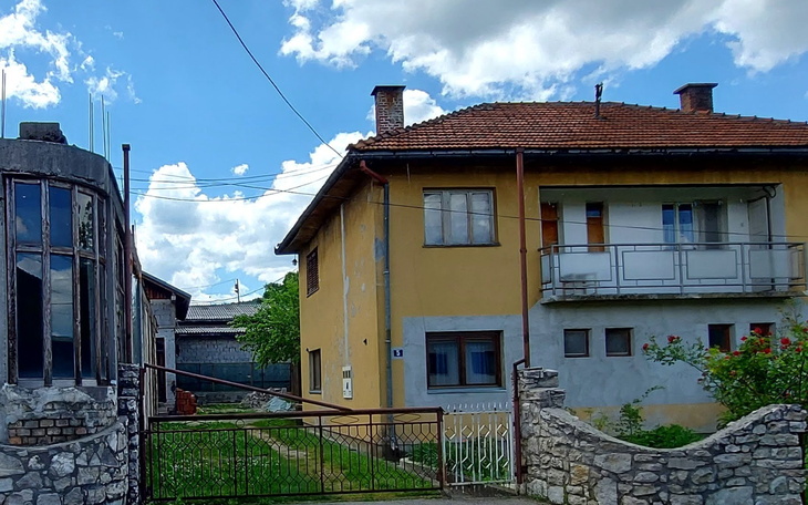 Dom z ogrodem, jasne niebo i chmury w tle.