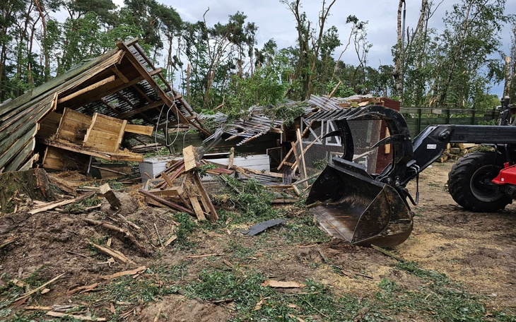 Zniszczony budynek po burzy, z widocznymi zniszczeniami i porozrzucanymi materiałami.