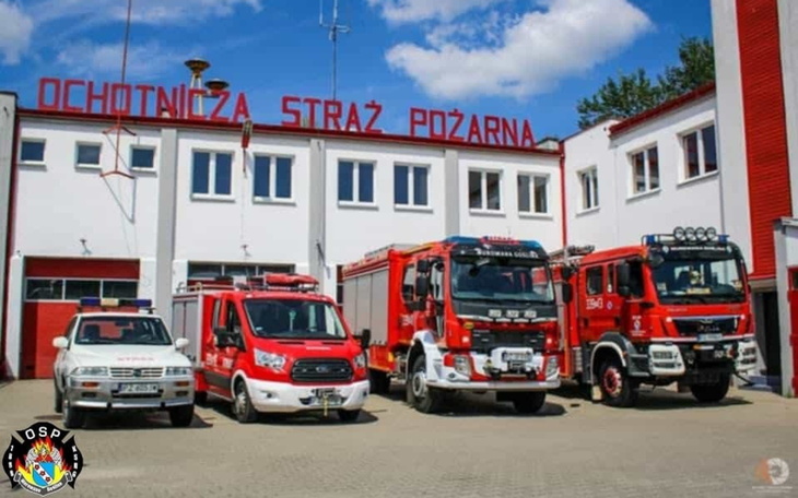 Budynek straży pożarnej z wozami strażackimi przed.