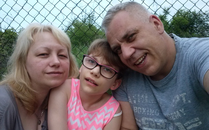 Rodzina pozująca do zdjęcia na tle ogrodzenia.