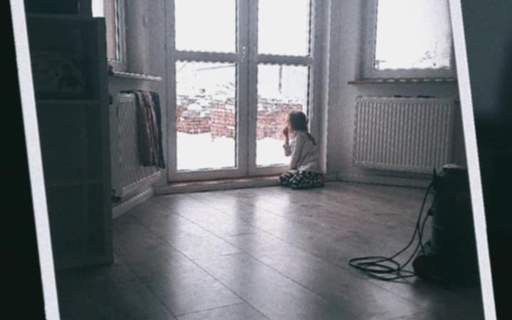 Dziewczynka siedząca przy oknie, patrząca na zewnątrz.