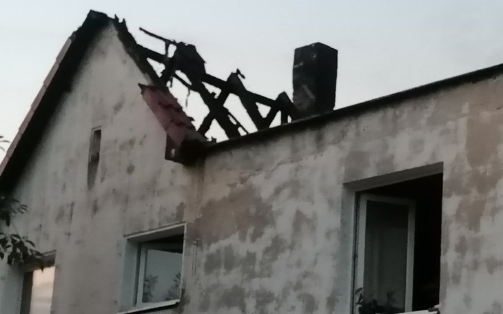 Zniszczony dach budynku po pożarze, widoczne uszkodzenia.