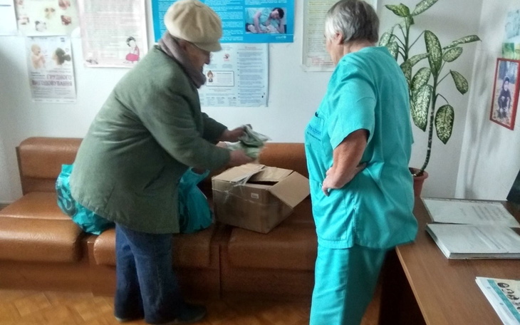 Dwie kobiety rozpakowują paczkę w biurze, otoczone dokumentami.