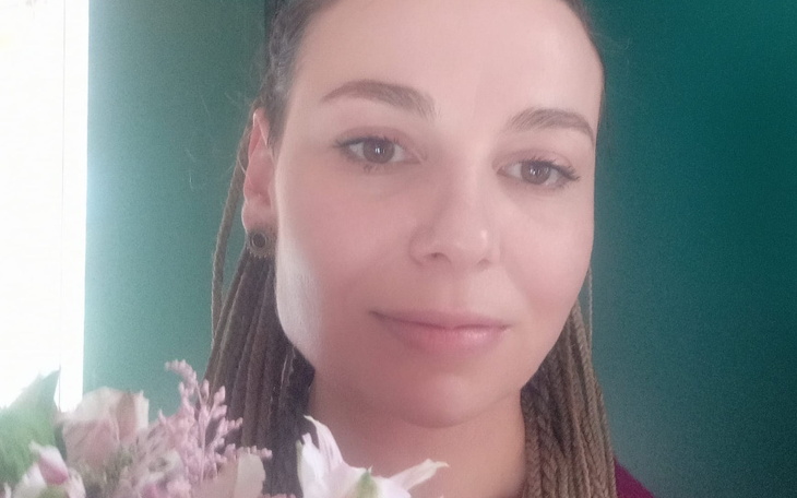 Kobieta z długimi włosami trzyma bukiet kwiatów.