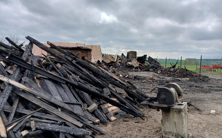 Zniszczona konstrukcja z drewnianymi belkami i zgliszczami.