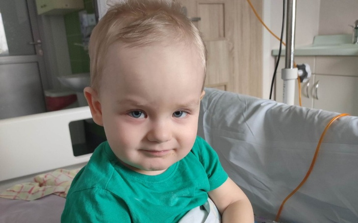 Mały chłopiec w szpitalnym łóżku, uśmiechający się.