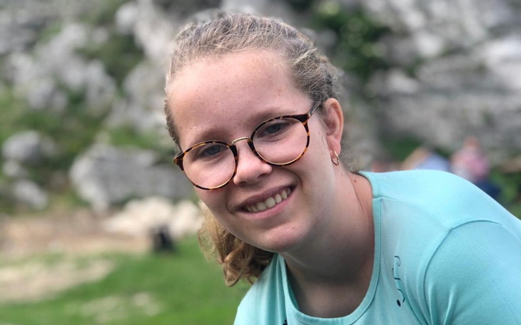 Uśmiechnięta dziewczyna w okularach, na tle zielonej trawy.