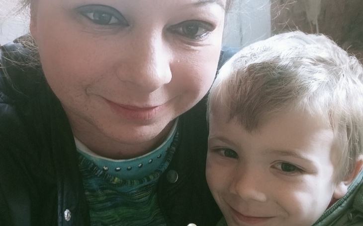 Matka z synem, oboje uśmiechnięci, w przytulnej scenerii.