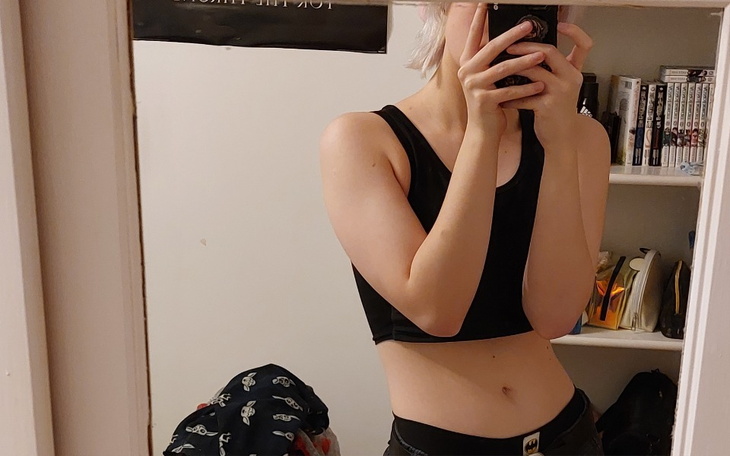 Osoba w czarnym topie, robiąca selfie w lustrze.