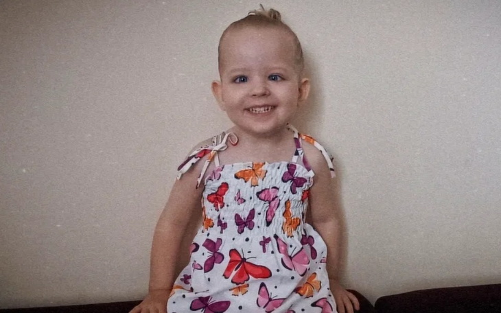 Mała dziewczynka w kolorowej sukience, uśmiechająca się do kamery.