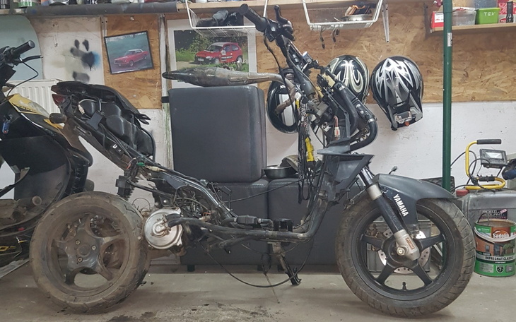 Uszkodzony skuter w warsztacie, części rozłożone do naprawy.