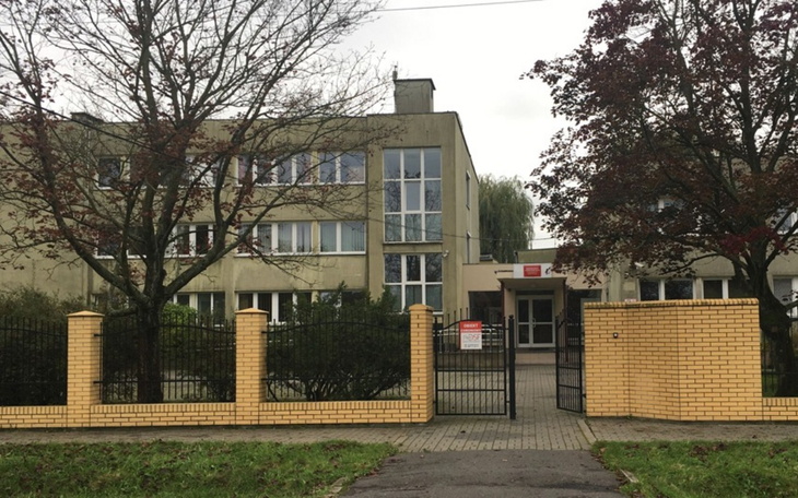 Budynek z ogrodzeniem, widok na wejście do instytucji.