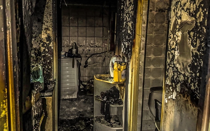 Zniszczona kuchnia po pożarze, z popiołem i uszkodzeniami.