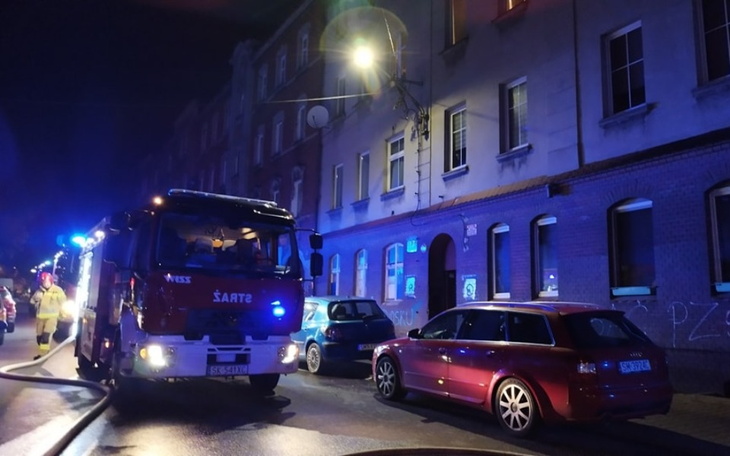 Wóz strażacki na ulicy w nocy, z niebieskimi światłami.