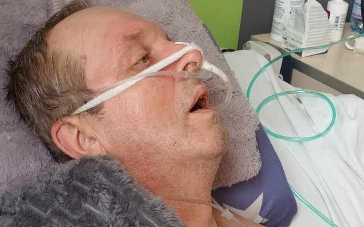 Mężczyzna w szpitalu, z rurkami tlenowymi.