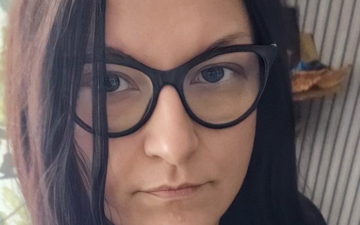 Portret kobiety w okularach, poważny wyraz twarzy.