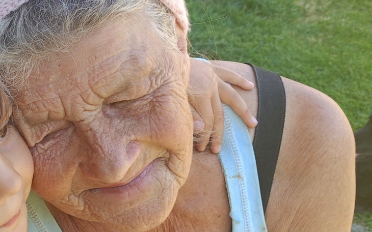 Starsza kobieta z uśmiechem, przytulająca dziecko.