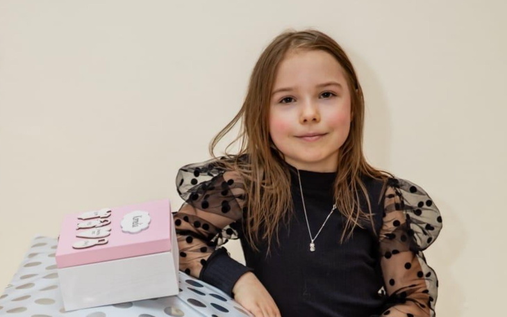 Młoda dziewczynka pozująca z prezentem na stole.