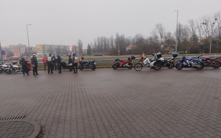 Motocykliści stojący przy drodze w deszczowy dzień.