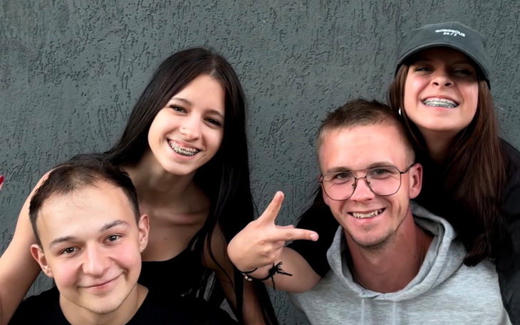 Grupa młodych ludzi pozujących razem na tle szarej ściany.